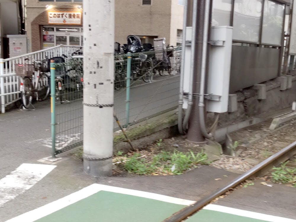 都電の線路を渡りきるとすぐに右手に自転車置き場と緑のフェンスに挟まれた緩やかなスロープが出てきます。そのスロープを上がります。
