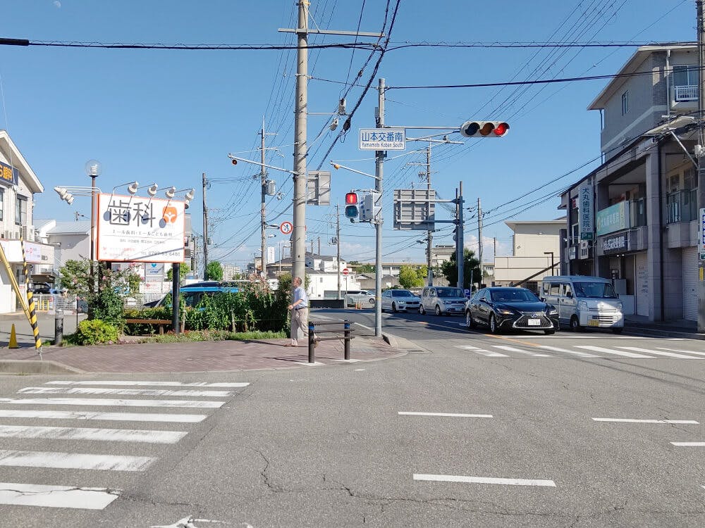 「山本交番南」交差点の信号の手前を左に曲がります。