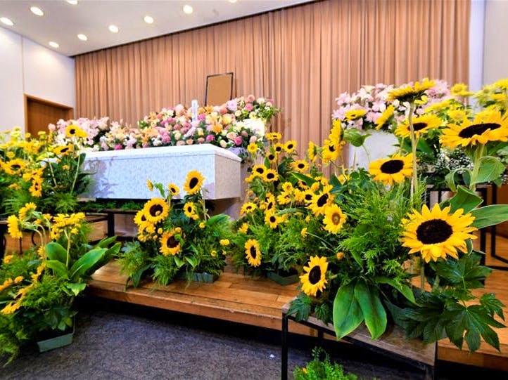 ひまわりを中心にした花祭壇。遺影の周りには白やピンク・黄色の花々が飾られている