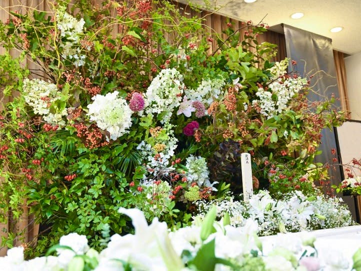 緑や白を基調とした花祭壇。背の高い木々の中に赤い実や花が使われている